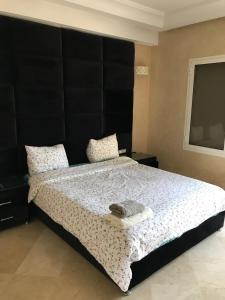 - une chambre avec un grand lit et une tête de lit noire dans l'établissement Villa 33 haut standing Avec piscine et Hammam, à Tanger