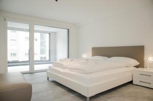 a white bedroom with a white bed and a window at Apartment JungfrauCenter Brienzersee - GRIWA RENT in Interlaken