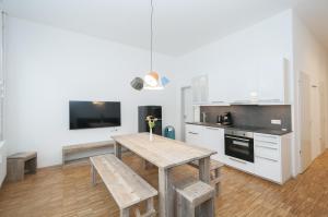 a kitchen with a wooden table with benches and a tv at Appartements an der Elbphilharmonie contactless Check in in Hamburg