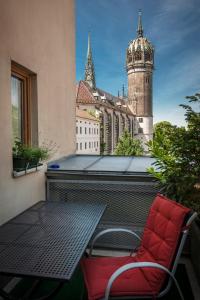 Ferienwohnungen am Schloss في لوفرستادت فيتنبرغ: كرسي احمر جالس على بلكونه مع مبنى