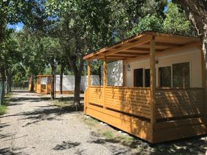 a row of wooden lodges under trees on a sidewalk at Camping Taimì in Marina di Massa