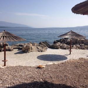 a beach with two umbrellas and the ocean at Villa Matovica in Kampor