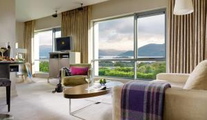 a living room with a couch and a large window at Aghadoe Heights Hotel & Spa in Killarney