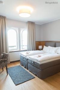 a bedroom with a large bed with a blue rug at Cottage Rheingau Hotel in Walluf