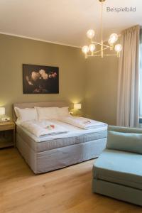 ein Schlafzimmer mit einem Bett mit einem Kronleuchter und einem Stuhl in der Unterkunft Cottage Rheingau Hotel in Walluf