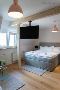 a bedroom with a large bed and a flat screen tv at Cottage Rheingau Hotel in Walluf
