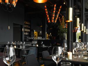 a restaurant with tables and chairs with wine glasses at 25hours Hotel Hamburg HafenCity in Hamburg