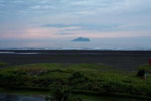 an island in the ocean with a mountain in the distance at Hai Tan Feng Qing in Toucheng