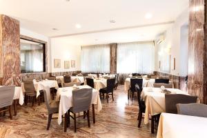 una sala da pranzo con tavoli e sedie bianchi di Hotel Corolle a Firenze