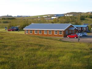 a large orange building with cars parked in a field at Skipalaekur Guesthouse in Egilsstadir