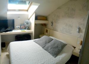 a small bedroom with a bed and a desk at Logis Arcombelle in Montigny-le-Roi