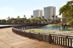 a boardwalk in a park with a pond of water lilies at Shangri-La Serviced Apartments, Yangon in Yangon