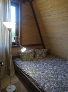 a bed in a room with a lamp and a window at Нарочанская хатка 2 in Narochʼ