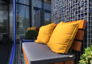 un banco con 2 almohadas amarillas en el balcón en Hotel Vier Jahreszeiten Lübeck, en Lübeck