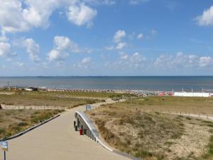 een loopbrug naar het strand met de oceaan op de achtergrond bij Appartementen Zeezicht in Katwijk aan Zee