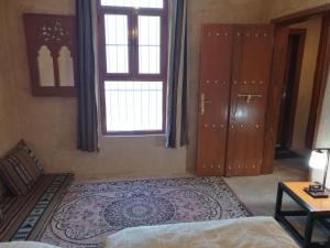 a bedroom with a bed and a window and a rug at Durrat Al-Misfah Guest House in Misfāh