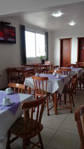 uma sala de jantar com mesas e toalhas de mesa brancas em Hotel São Paulo em Rio Grande