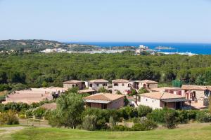 un pueblo en una colina con el océano en el fondo en S'Incantu Resort en Villasimius