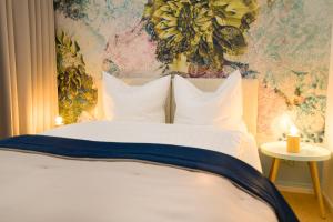 a bed with white pillows and a floral wall at Hotel Reverey * kontaktloser Self Check-In * in Hannover
