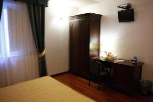 a bedroom with a desk and a cabinet and a bed at Hotel Teocrito in Siracusa