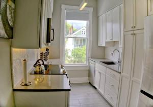 Beautiful Brick 2 Bedroom Home في سافانا: مطبخ بدولاب بيضاء ومغسلة ونافذة