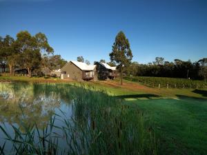 a house with a pond in front of it at Hermitage Lodge in Pokolbin