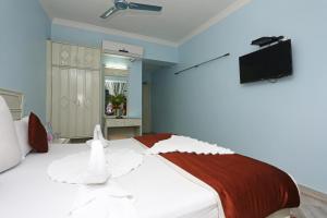 a bedroom with a white bed and a flat screen tv at Hotel Niladri in Puri