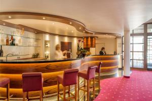 a restaurant with a bar with purple chairs at INVITE Hotel Löwen Freiburg in Freiburg im Breisgau