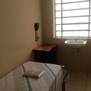 a bedroom with a bed and a sink and a phone at Hotel Chaves - Quartos Individuais in Sao Paulo