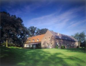 um grande celeiro com um grande campo verde à sua frente em Romantik Hotel Kasteel Daelenbroeck em Herkenbosch