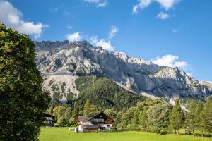 a house in a field in front of a mountain at Hotel Pension Residence in Ramsau am Dachstein