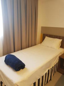 a white bed with a blue towel on it at Flat Olímpia Park Resort in Olímpia +16 photos