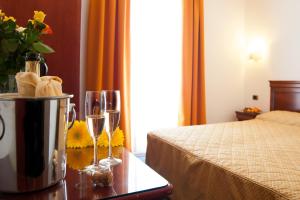 una camera d'albergo con letto e tavolo con bicchieri da vino di Hotel Bologna a Bardolino