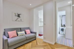 a living room with a gray couch and pink pillows at CMG Montorgueil/ Grands Boulevards in Paris