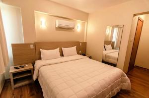 um quarto de hotel com uma cama grande e um espelho em Hotel Almanara em Rio Grande