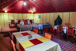 a dining room with tables and chairs in a tent at Sahara Desert Luxury Camp in Merzouga