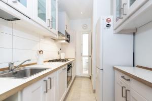 a kitchen with white cabinets and a sink and a refrigerator at Comfortable and Convenient apt in the center - Zanobi Delux in Florence