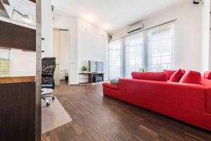 a living room with a red couch and a chair at Life Apartment & City Bike in Bolzano