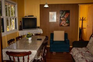 a living room with a table and chairs and a tv at Nossa casa em Canela in Canela