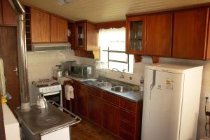 a kitchen with wooden cabinets and a white refrigerator at Nossa casa em Canela in Canela
