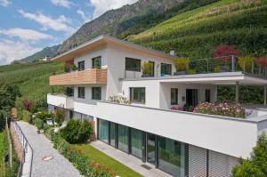 une maison sur une colline avec des montagnes en arrière-plan dans l'établissement Weinreichhof, à Castelbello