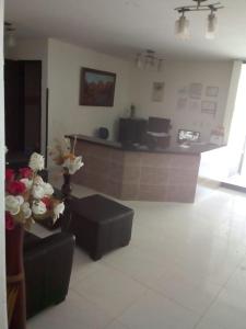 a lobby with a counter and flowers in a room at Hotel T&aacute;chiras in Bucaramanga