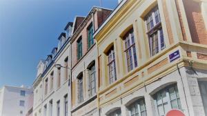 un bâtiment jaune et blanc dans une rue de la ville dans l'établissement Appart Hôtel Lille Baudoin, à Lille