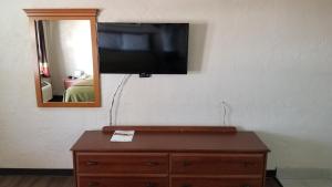 a flat screen tv on a wall with a wooden dresser at Deluxe Inn - Sarasota in Sarasota
