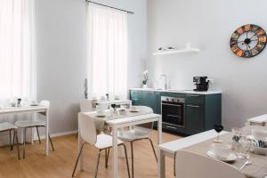 a dining room with white tables and chairs and a clock at Elysium B&B in Messina