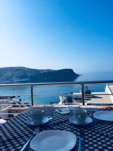 a table with plates and cups and a view of the ocean at Vila Kosteli in Himare