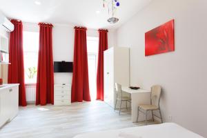 Schlafzimmer mit roten Vorhängen sowie einem Tisch und Stühlen in der Unterkunft Basseynaya Apart Hotel in Kiew