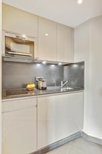 - une cuisine avec des placards blancs et un évier dans l'établissement Luxury Apartment Paris Louvre, à Paris