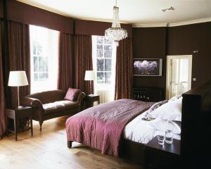 a bedroom with a bed and a couch and a chair at Stoke Place- Part of the Cairn Collection in Slough