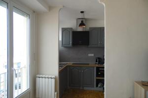 a kitchen with gray cabinets and a sink and a window at L' entre mer et falaise in Le Tréport